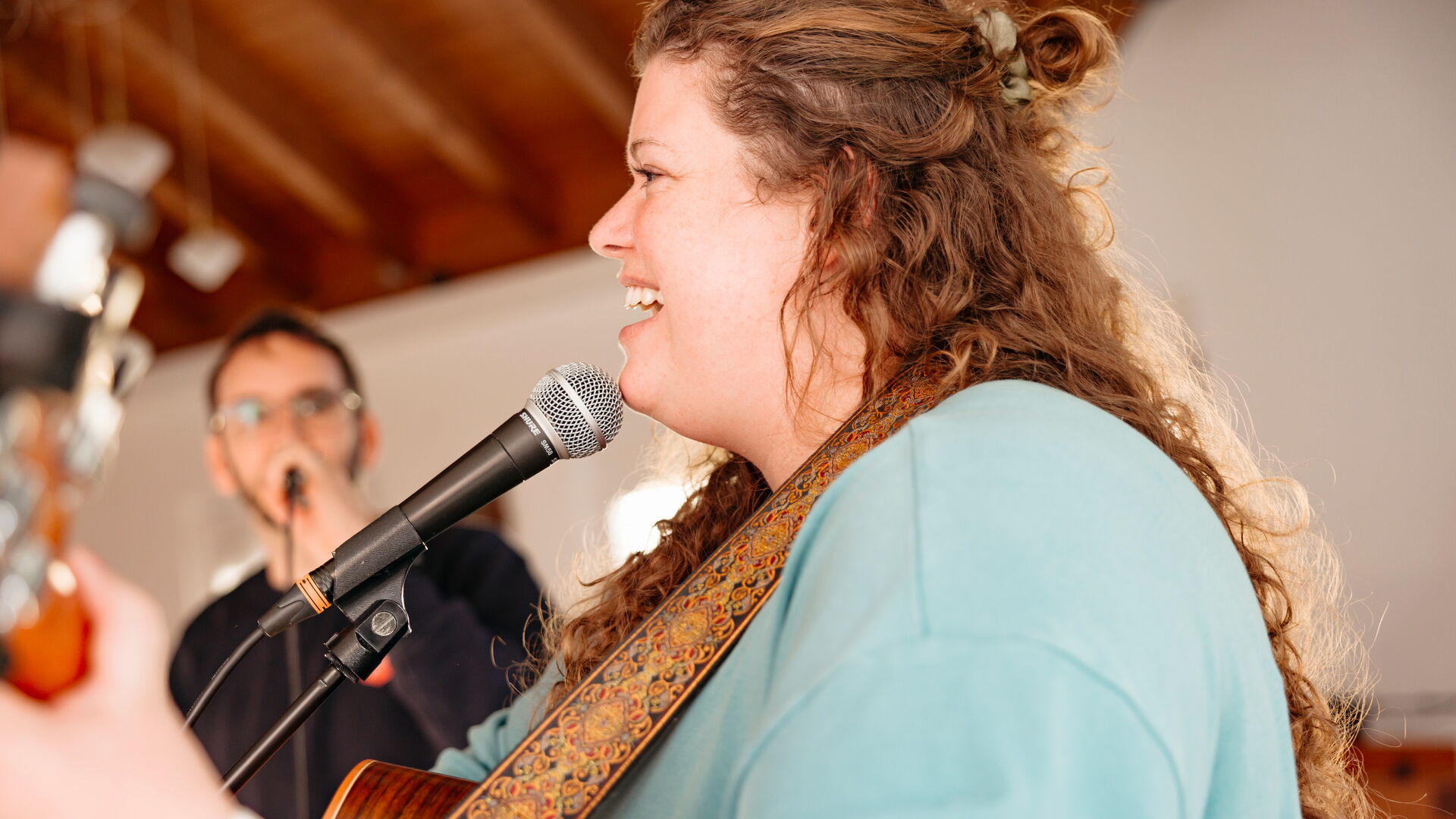 Eine Frau singt mit Gitarre in ein Mikrofon während eines Gottesdienstes der Heilsarmee Affoltern am Albis.