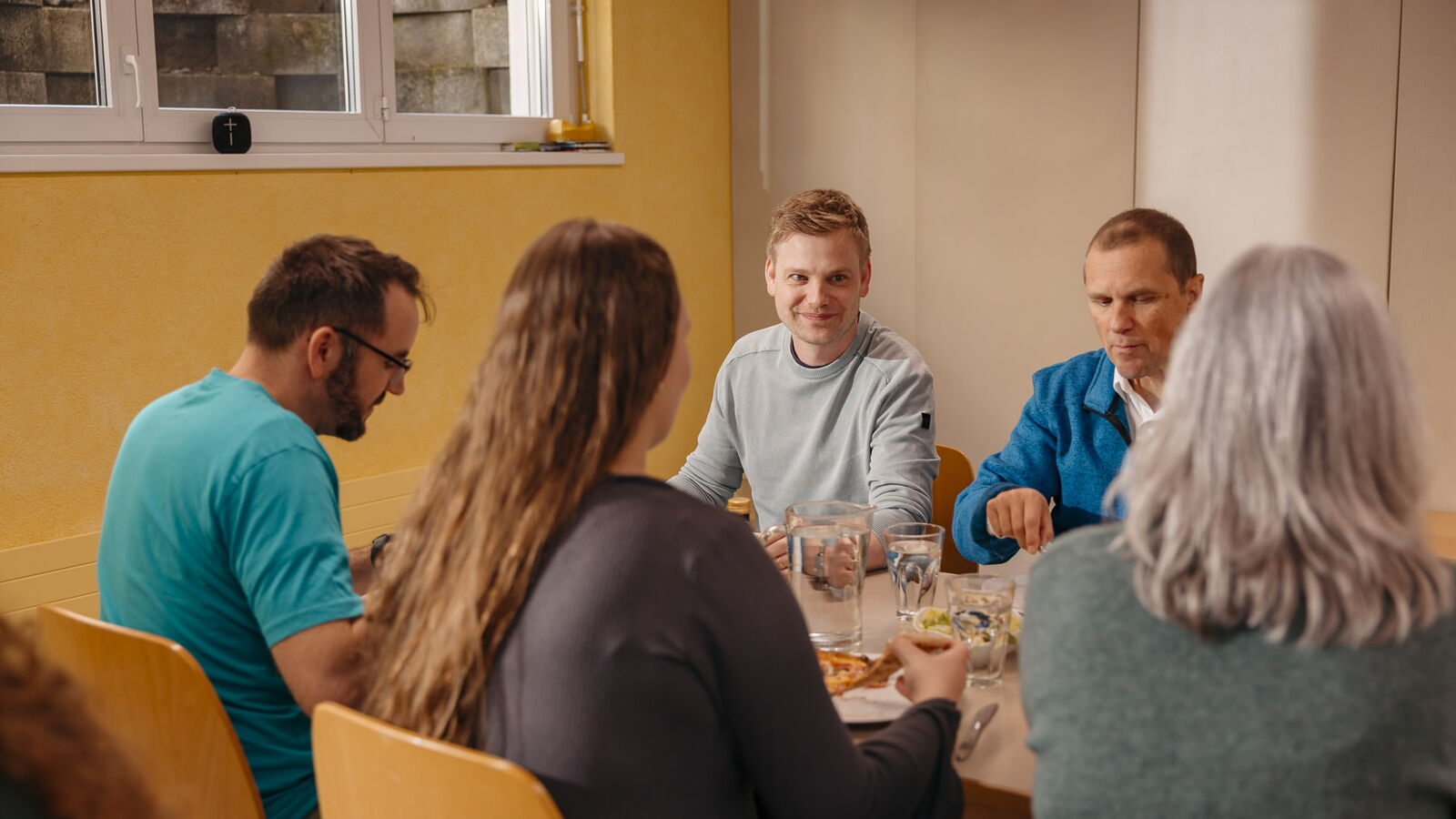 Mehrere Personen sitzen bei einem gemeinsamen Essen an einem Tisch bei der Heilsarmee Affoltern am Albis.